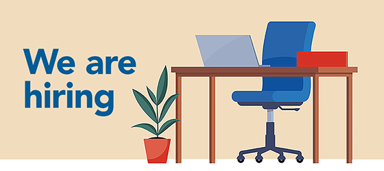 We are hiring. Desk with empty chair and laptop.